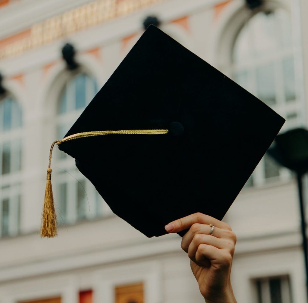 Image of someone holding up a graduation cap outside. This image shows how graduating can be a major life transition. work with a skilled life transitions therapist in Austin, TX to cope.