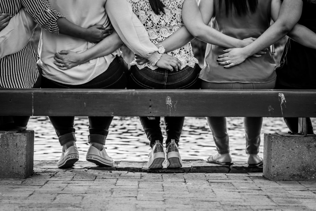 Image of a group of friends, sitting on a bench with their arms around each other. Discover how a therapist for transitions in Austin, TX can help you cope with the changes you face.