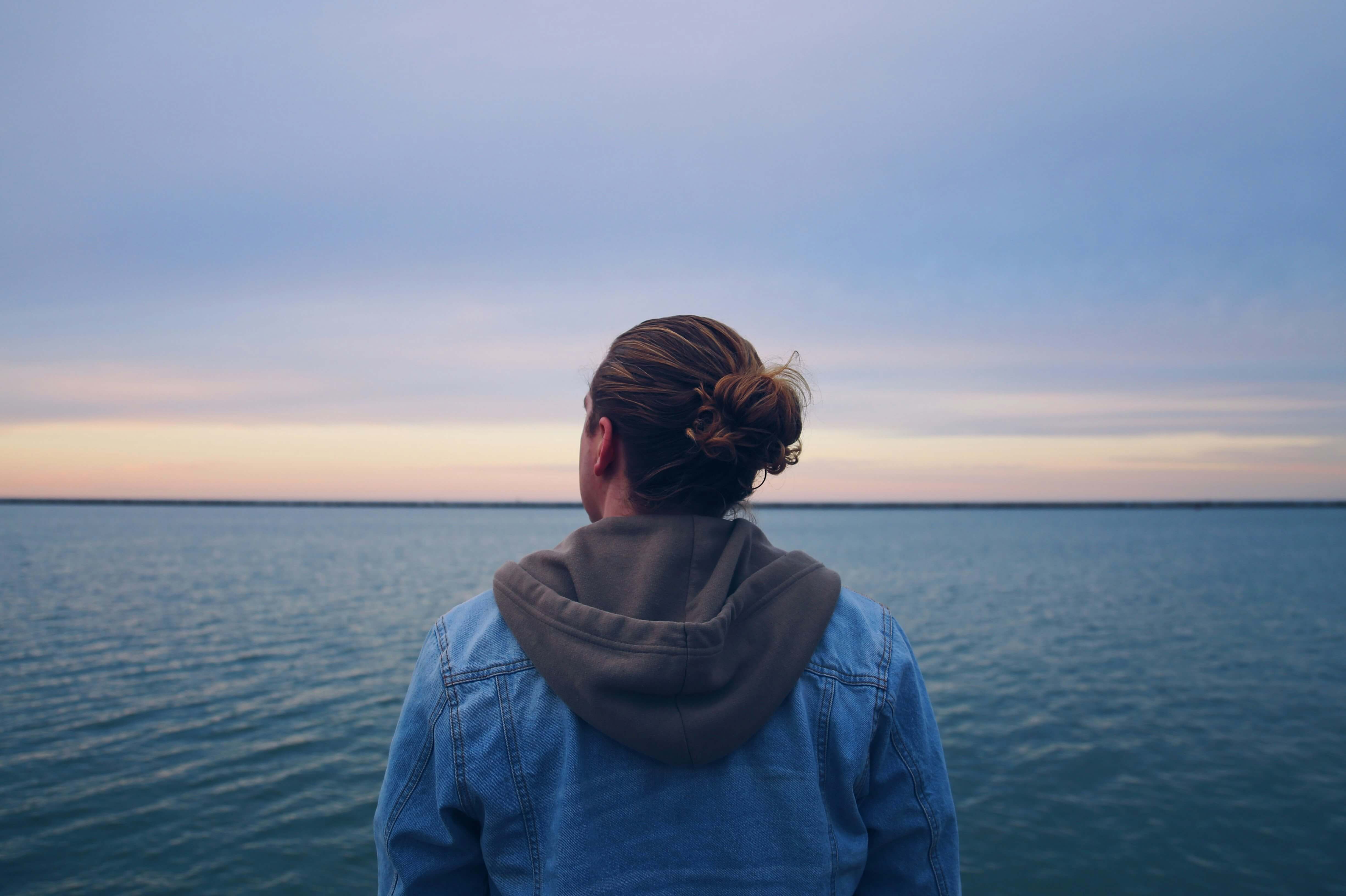 Image of a man looking out over the ocean in thoughts during sunrise. With the help of a life transition therapist in Austin, TX you can learn to cope and adapt with major life changes.