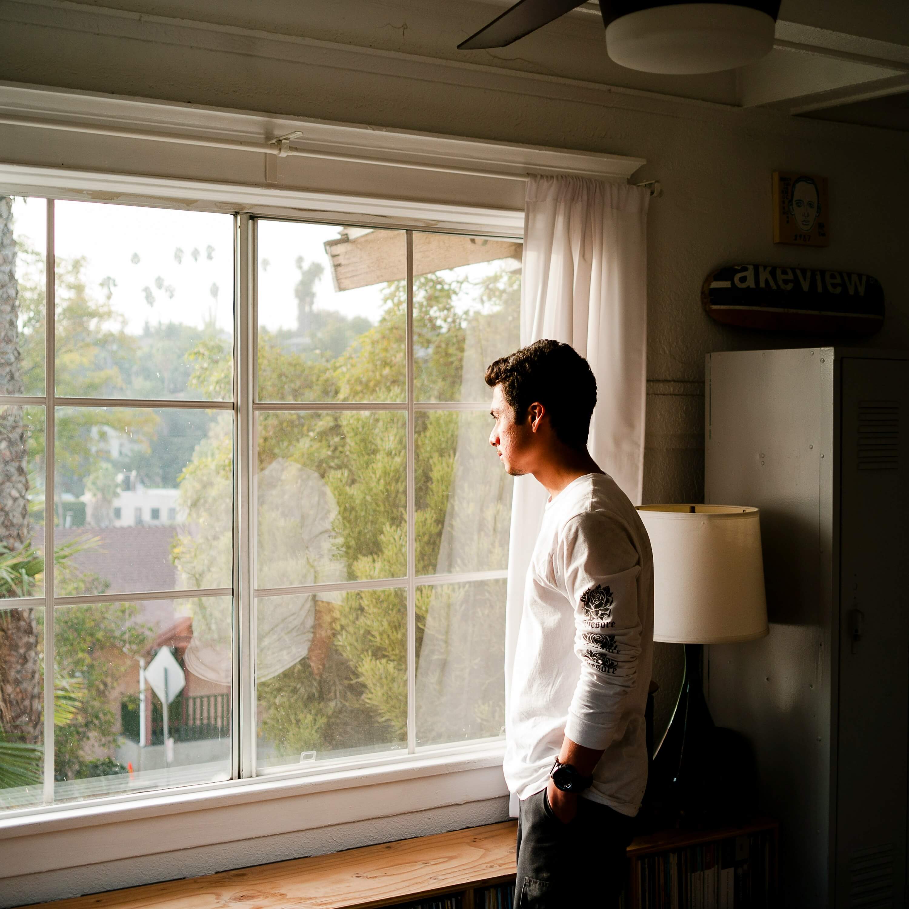 Image of a young man thinking and looking out a window. If you are trying to manage a major life change, discover how life transitions therapy in Austin, TX can help you manage their effects.