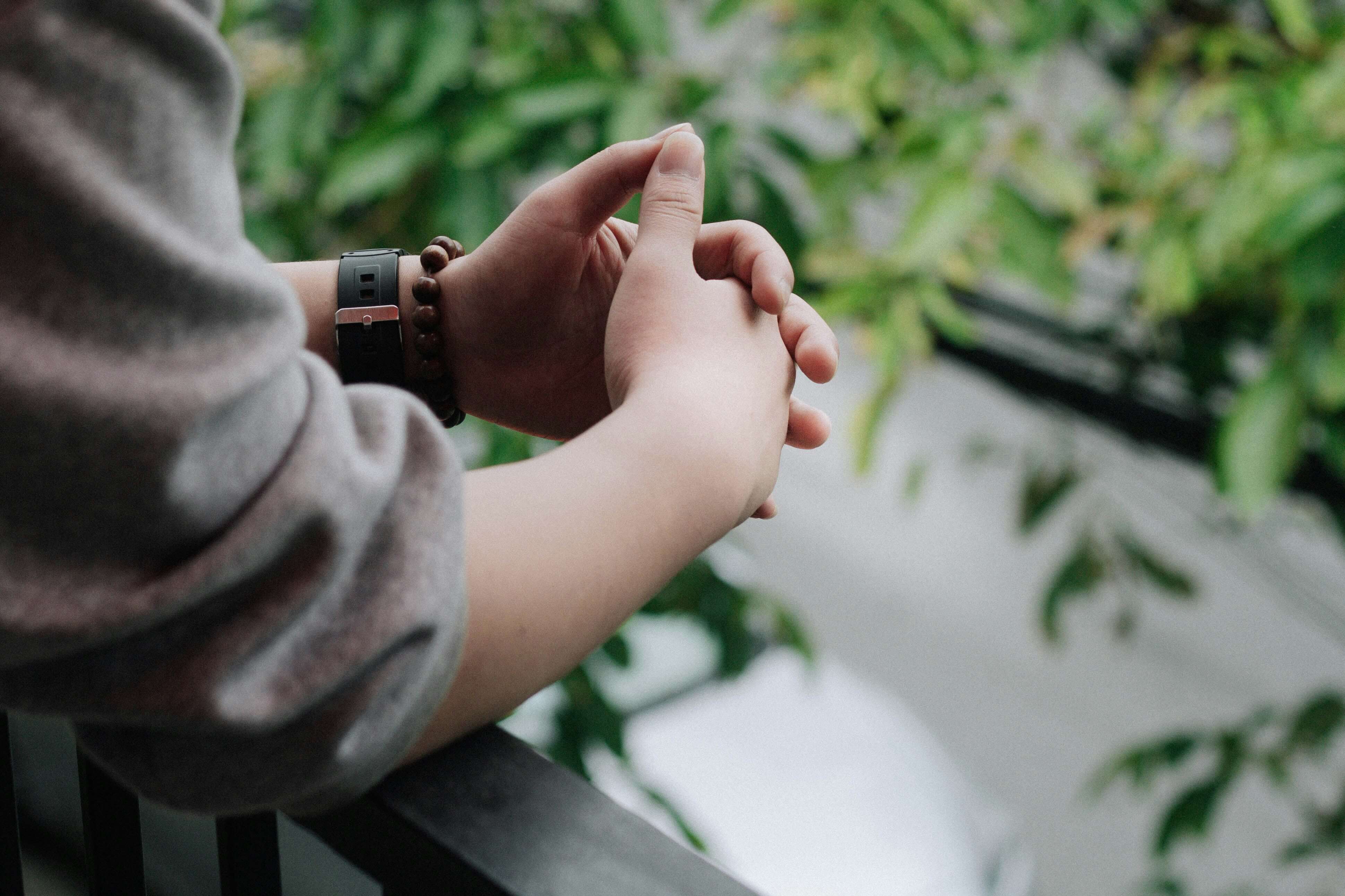 Image of someone leaning on a rail clasping their hands together. With the help of life transition therapy in Austin, TX you can learn ways to cope and adjust quickly.