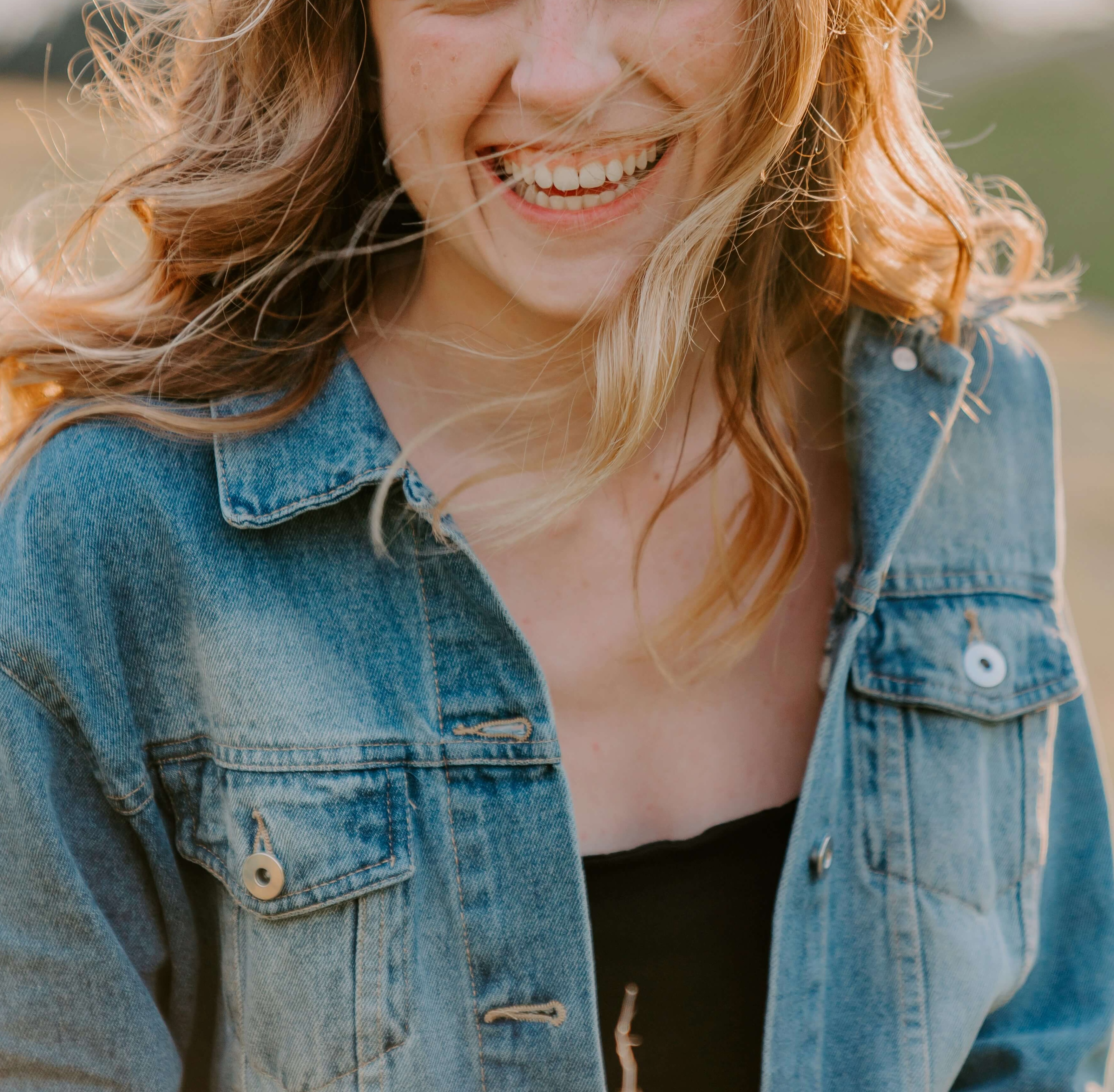 Image of a smiling woman standing outside on a sunny day. If you are transitioning into adulthood, find support in coping with the changes with life transition therapy in Austin, TX.